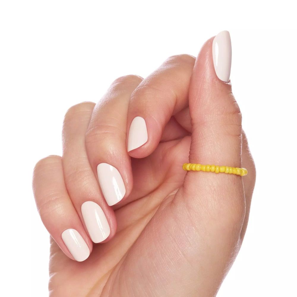 Main avec ongles vernis et bague jaune. Ongles rose clair.