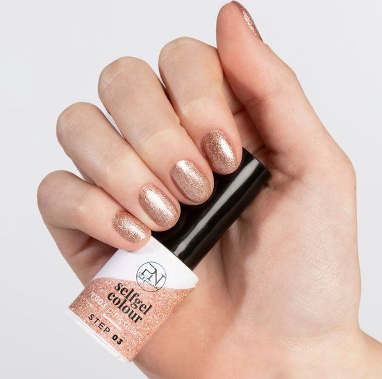 Main avec ongles vernis et flacon de vernis. Flacon avec inscription "selfgel colour" et "Pink Quartz".