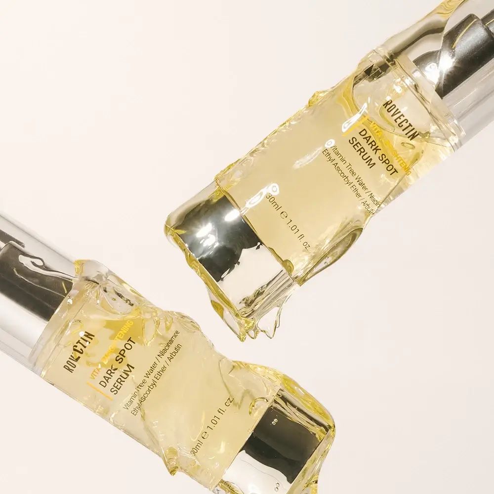 Twee serumflessen met pomp. Opschrift: ROVECTIN Vita Dark Spot Serum. Bevat vitamine water, niacinamide, ethyl ascorbyl ether, arbutine.