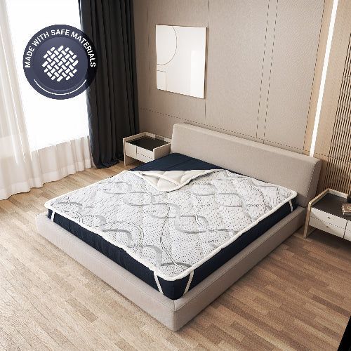 Matrasbeschermer op een bed, met zegel 'Made with safe materials'.