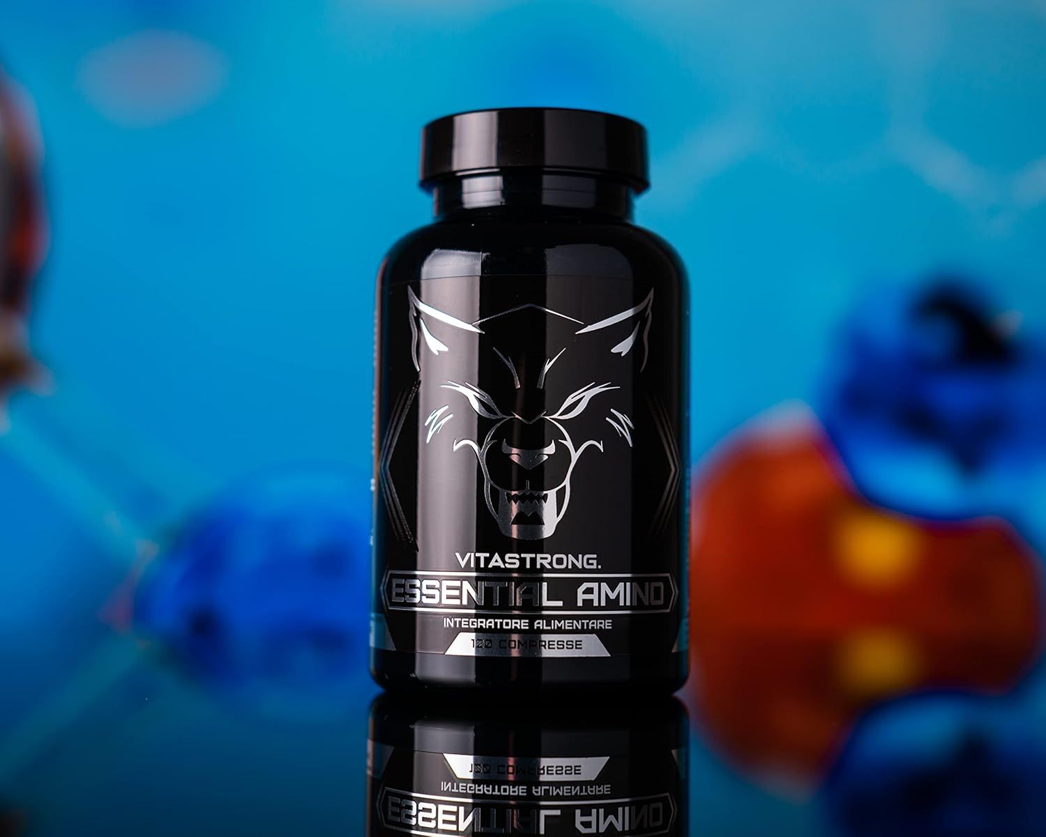 Flacon noir Vitastrong Essential Amino, comprimés en dessous. Inscription et logo loup. Fond bleu.