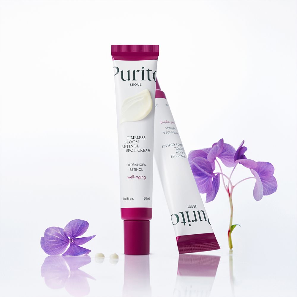 Deux tubes de Purito Retinol Spot Cream avec des fleurs.