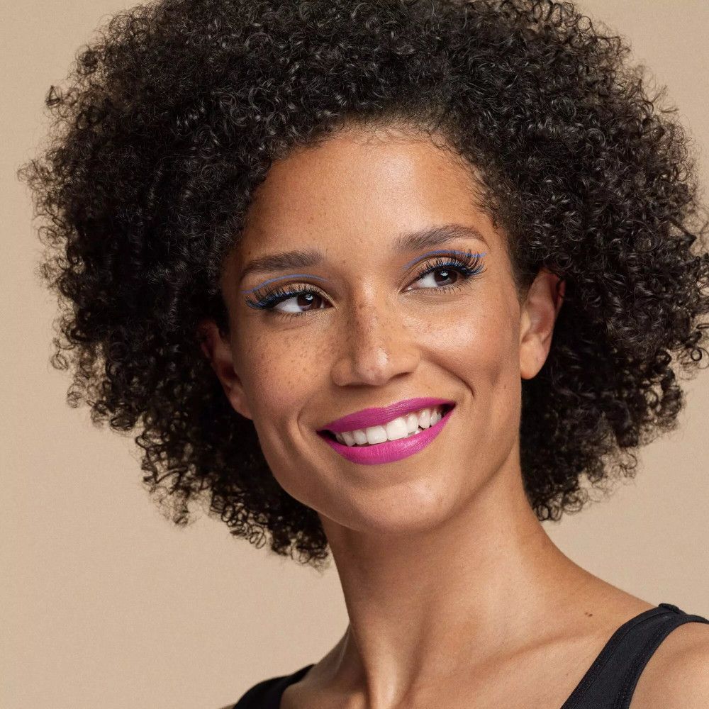 Portrait d'une femme souriante avec des lèvres roses et des cils bleus.