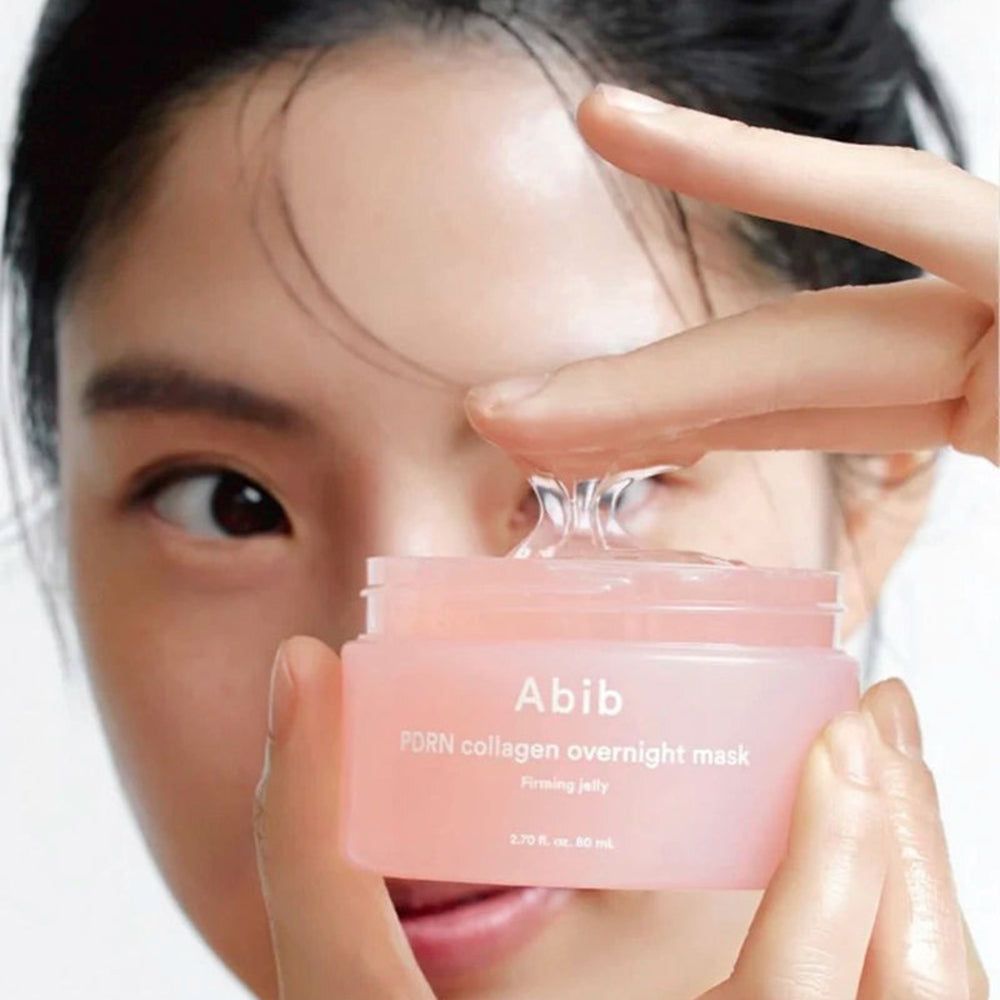 Pot rose avec gel transparent. Inscription : Abib PDRN collagen overnight mask. Une main tient le gel.