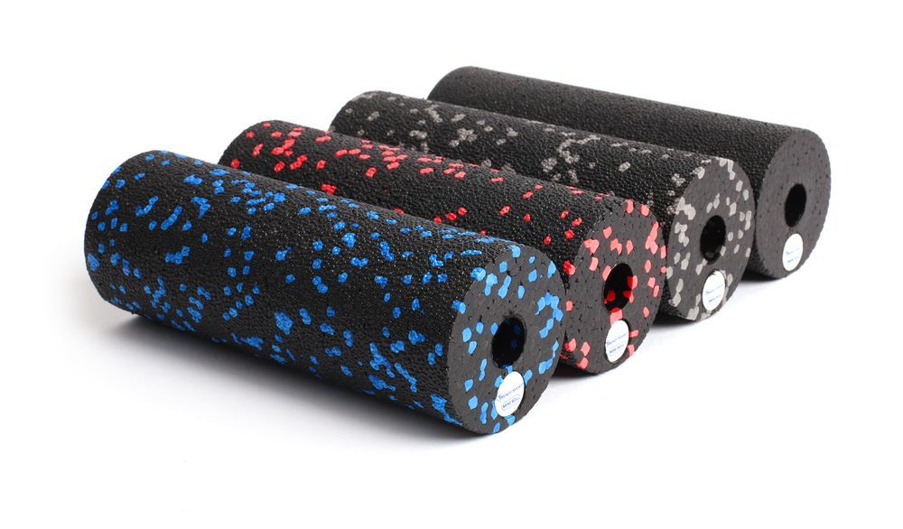 Cinq rouleaux de fascia de couleurs variées. Rouleaux bleus, rouges, gris et noirs avec trous. Sur fond blanc.