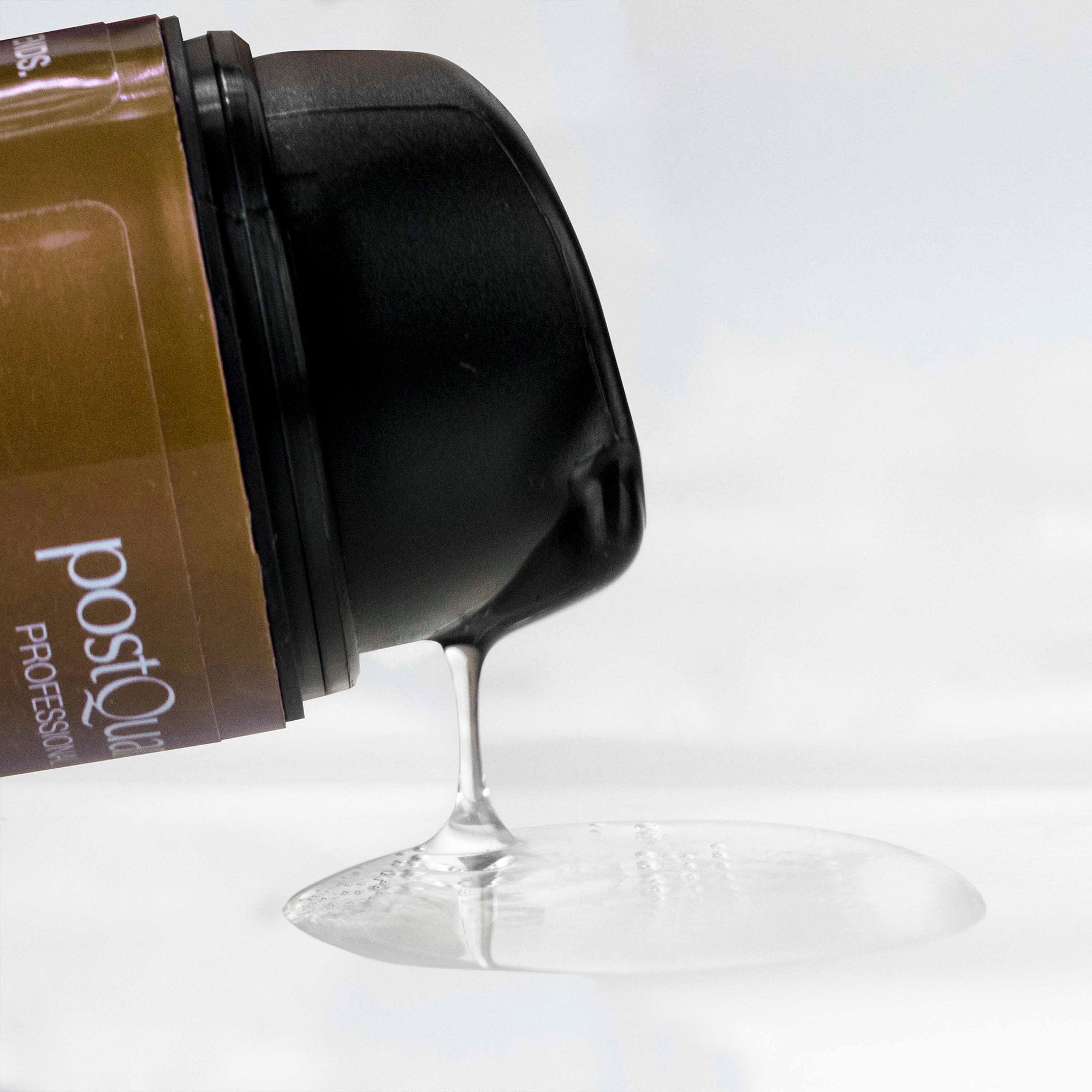 Haarserum wordt uit een fles gegoten. Heldere vloeistof. Merk: Postquam Professional.