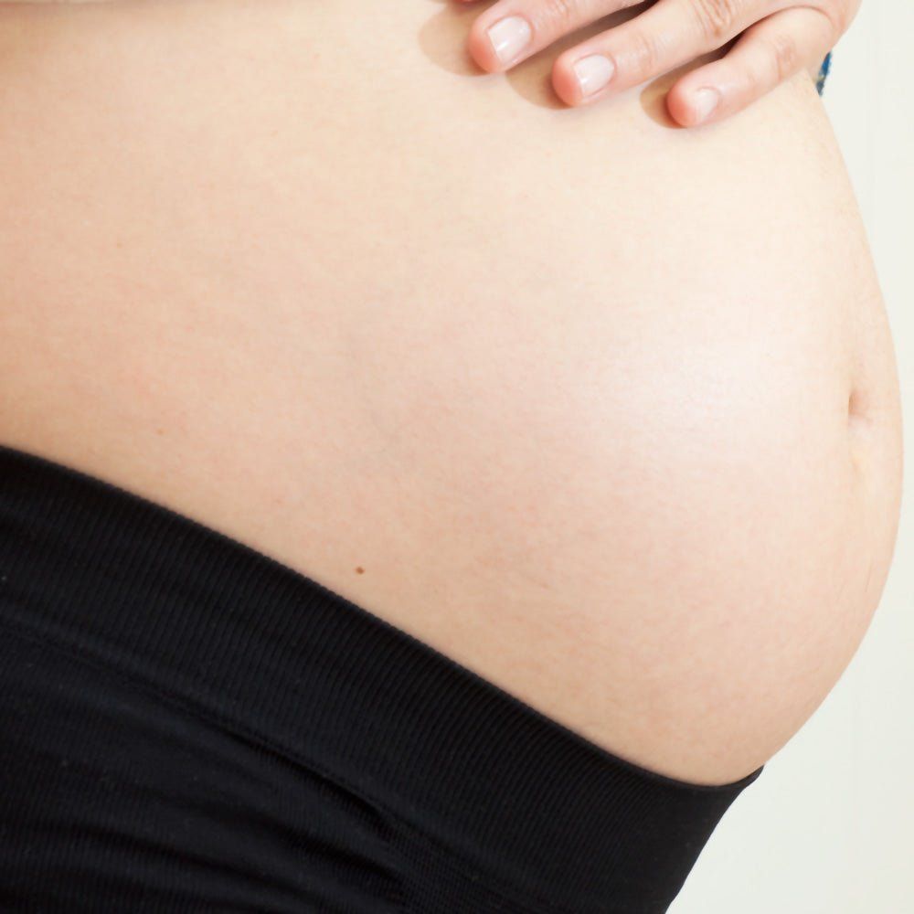 Tissu noir sur le ventre. Femme enceinte, gros plan sur le ventre.
