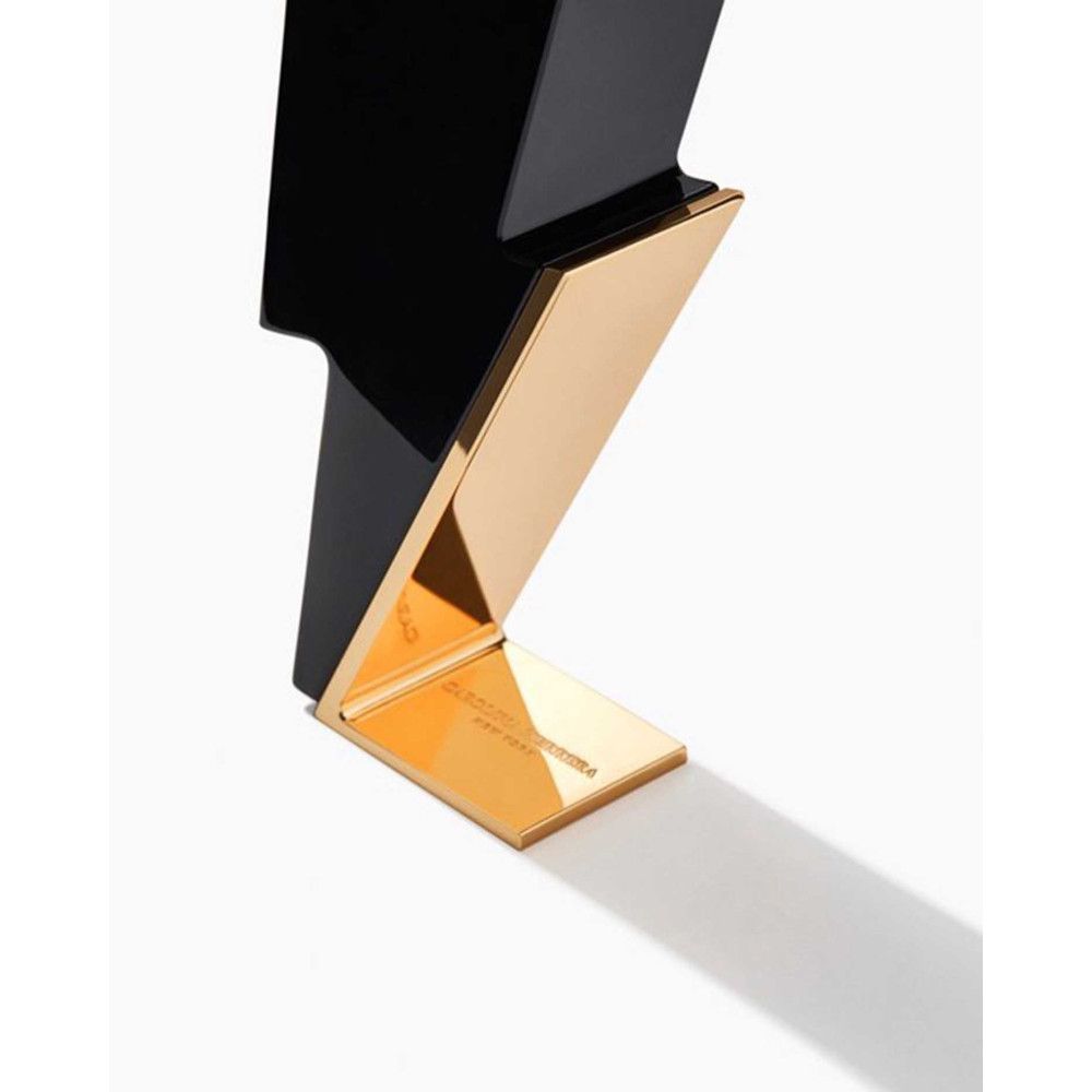 Flacon noir en forme d'éclair avec socle doré. Inscription sur le socle.