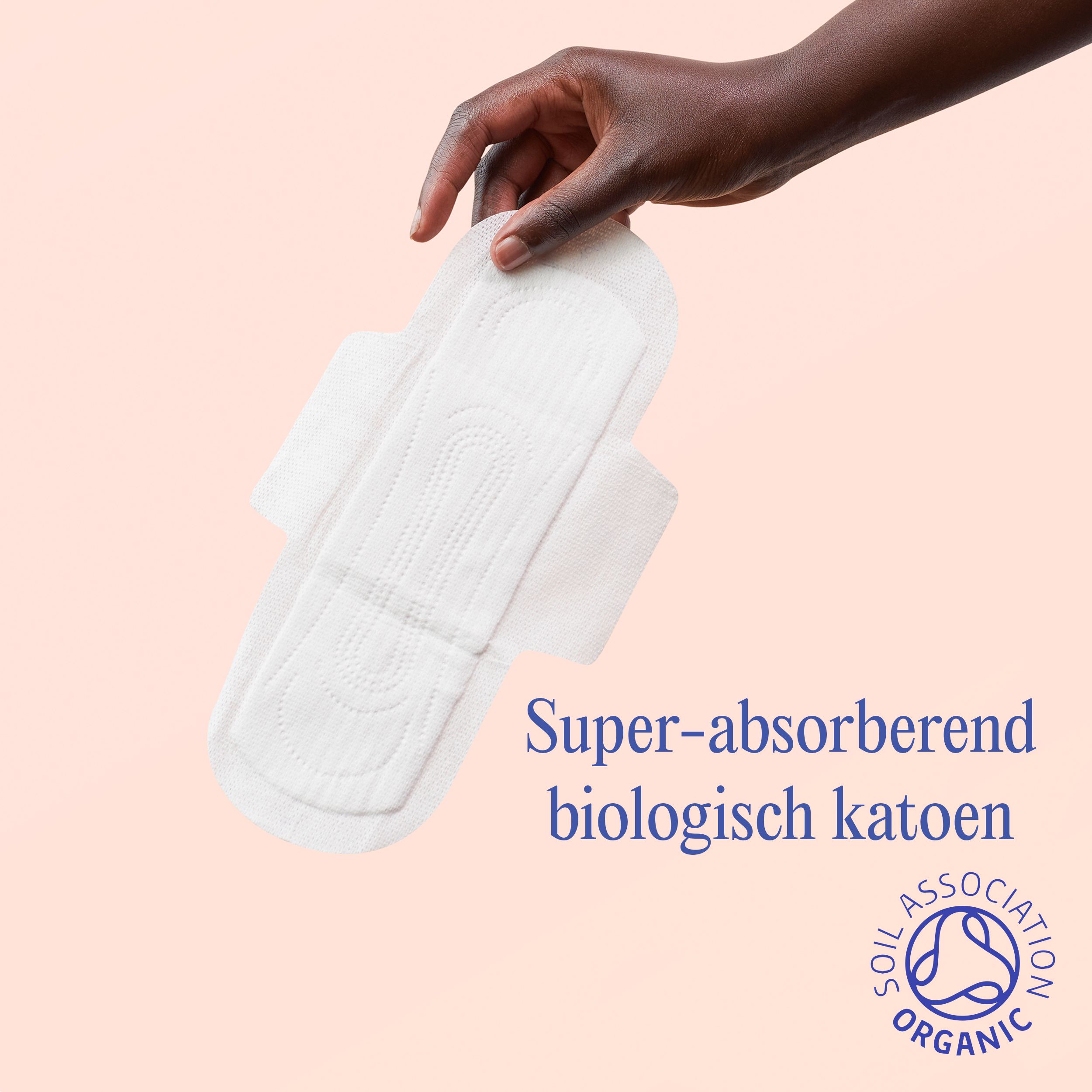 Hand houdt een wit maandverband vast. Opschrift: Super-absorberend, biologisch katoen. SOIL ASSOCIATION ORGANIC.
