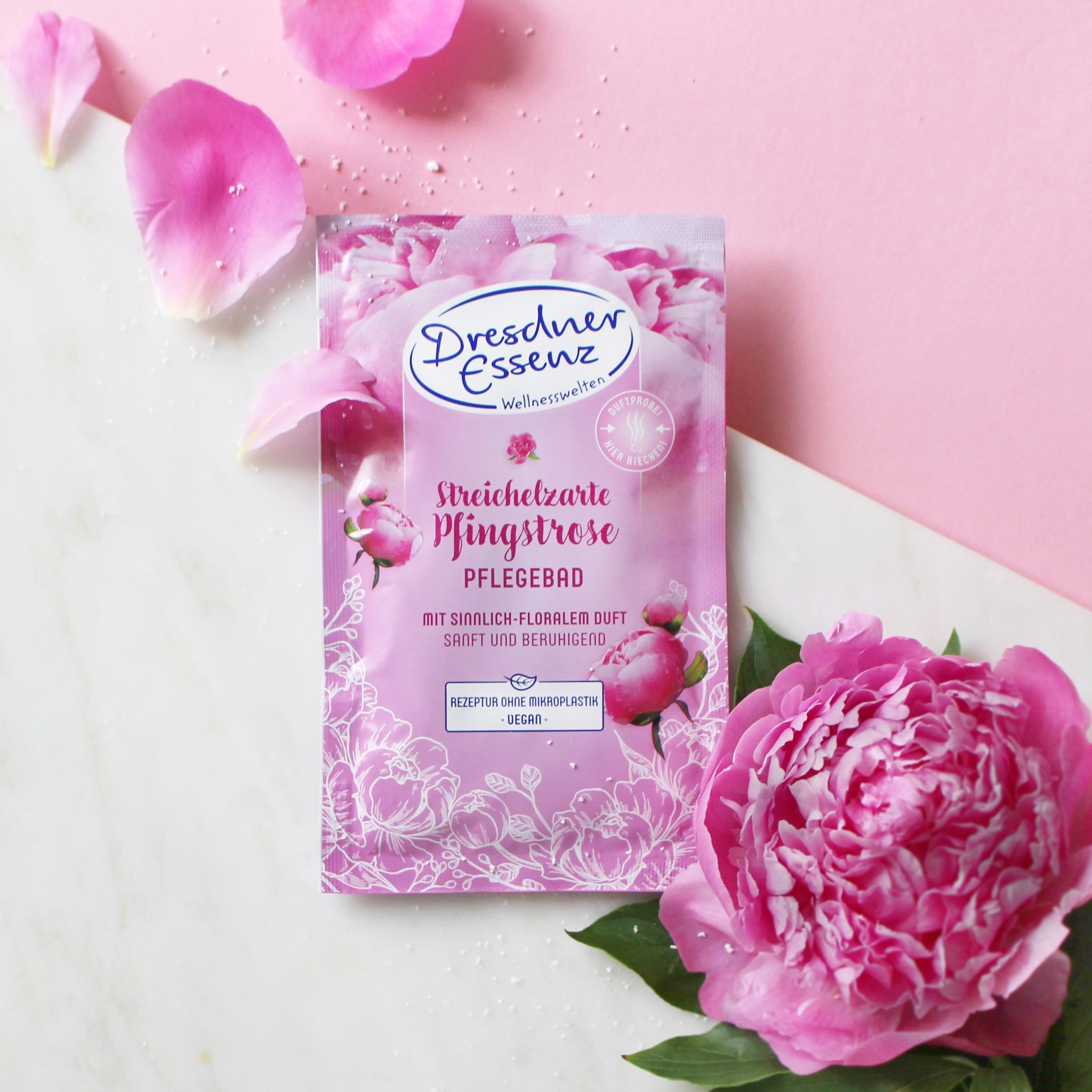 Sachet rose 'Dresdner Essenz' avec pivoine. Pétales et fleur en arrière-plan. Produit mis en avant.