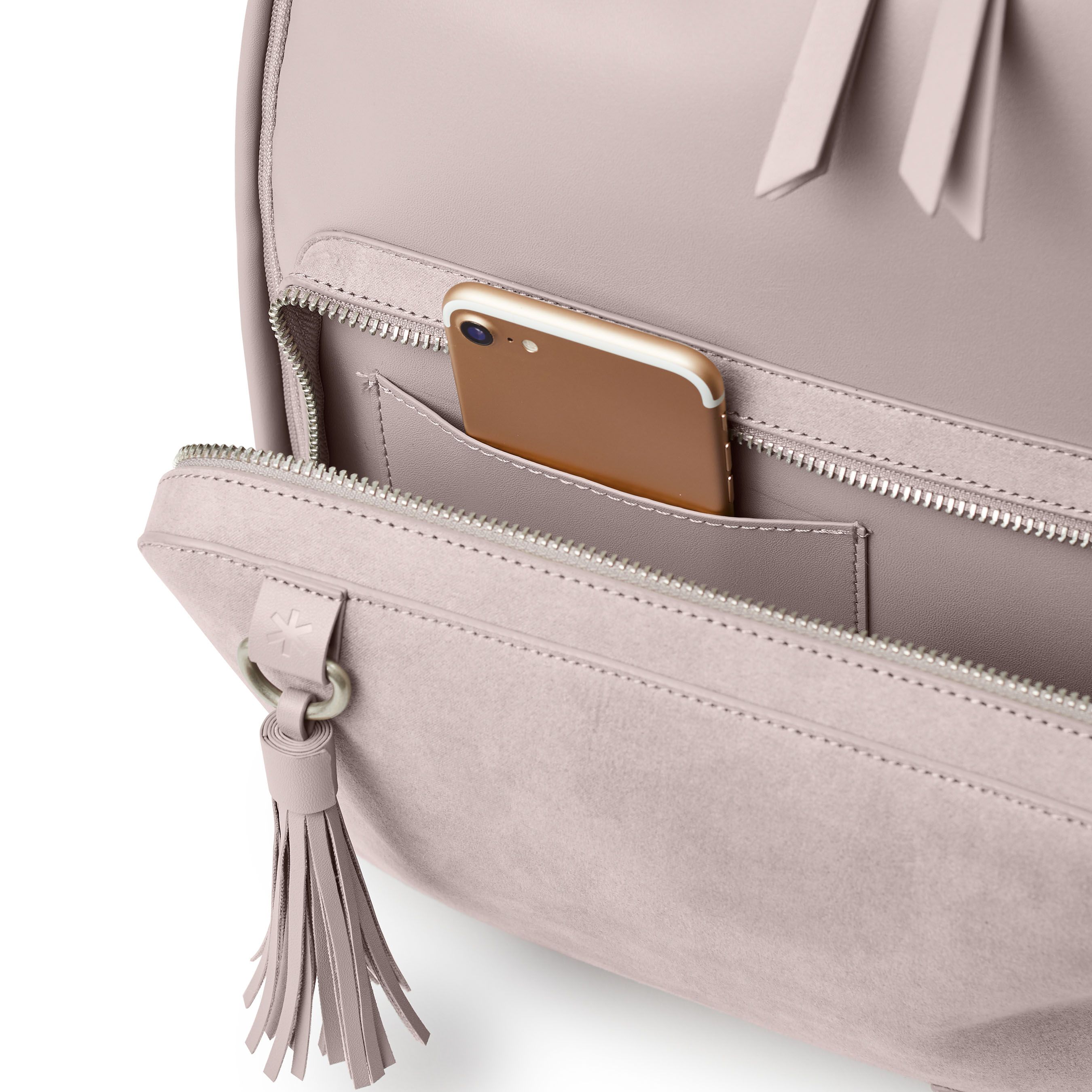 Lichtgrijze luiertas, detailweergave. Voorvak met ritssluiting. Smartphone in zak. Kwast.