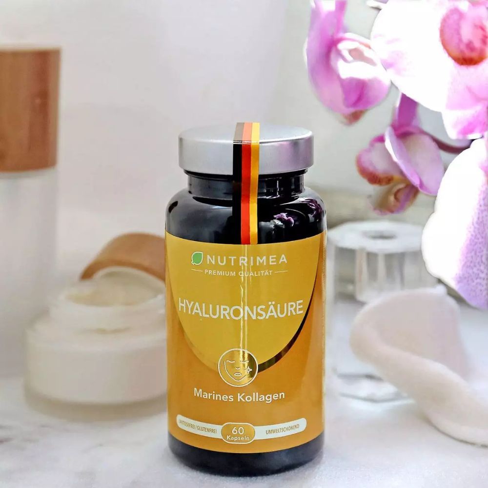 Bruine fles met capsules. Opschrift: Hyaluronzuur, Marine Collagen. 60 capsules. Op een tafel met decoratie.