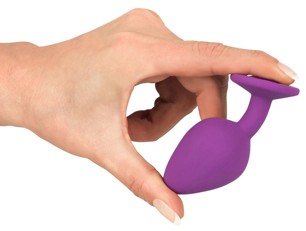 Plug anal violet avec bijou, tenu dans une main.