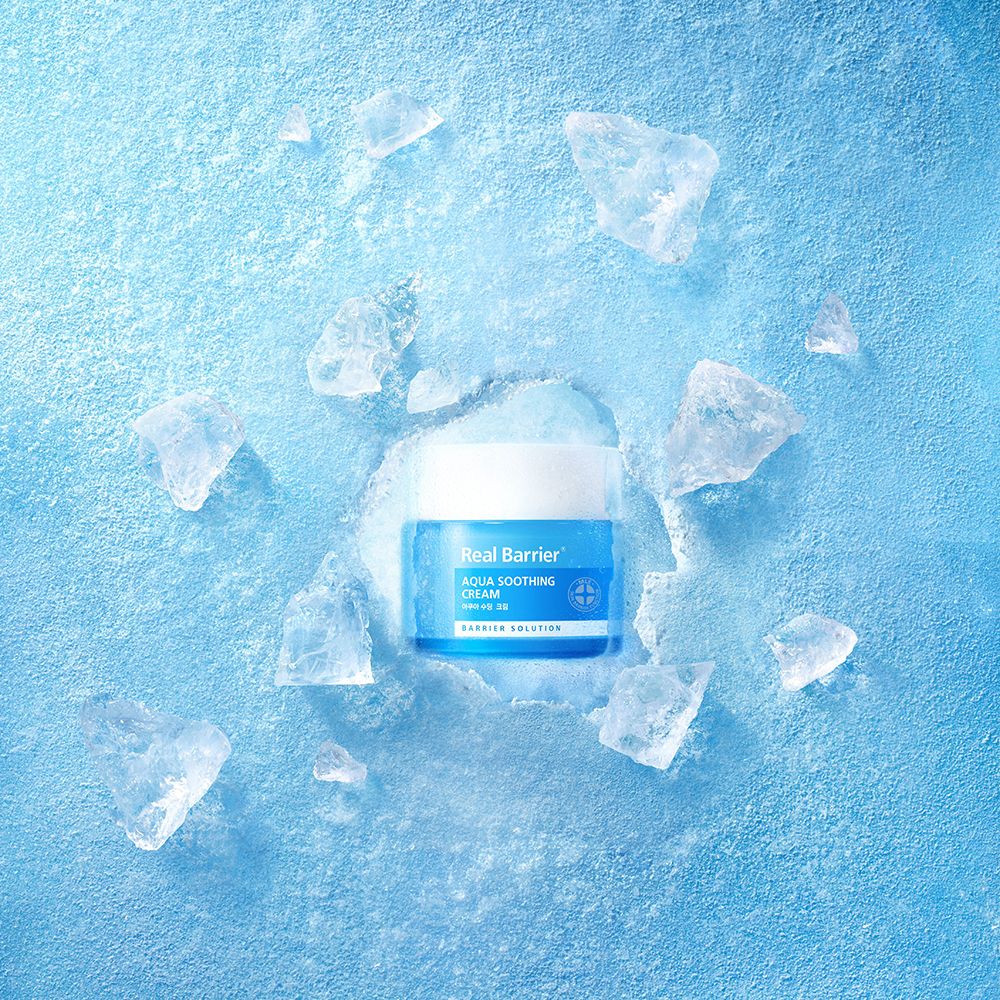 Pot de crème entouré de morceaux de glace sur fond bleu. Inscription "Real Barrier Aqua Soothing Cream".
