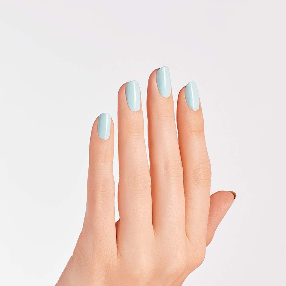 Main avec quatre ongles vernis en bleu clair. Les ongles sont de forme ovale et brillants. Fond blanc.