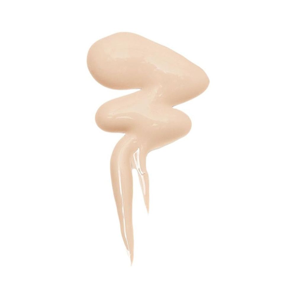 Goutte de correcteur beige. Texture liquide, en forme de vague. Sur fond blanc.