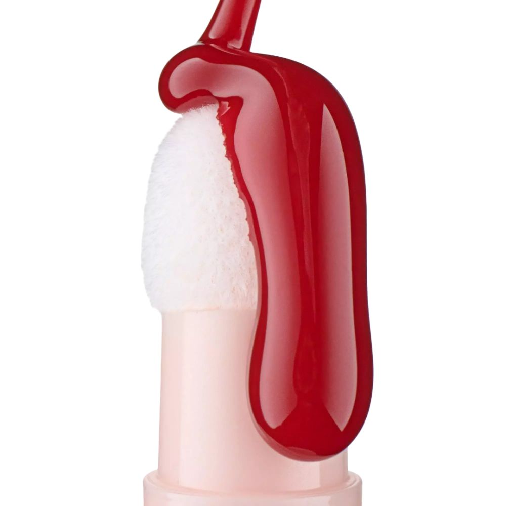 Close-up van een applicator met lipolie. Witte applicator met rode vloeistof. Roze houder.