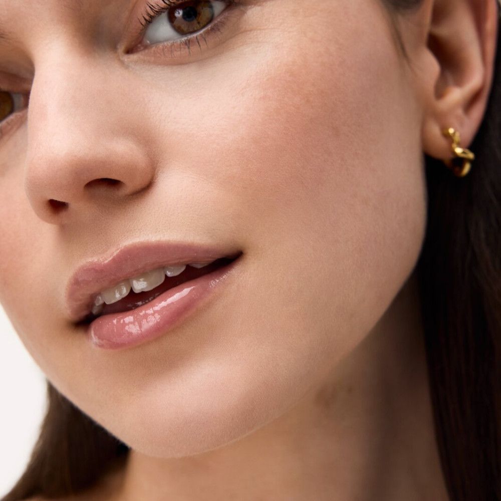 Close-up van een gezicht met glanzende lippen. Lipelixer op de lippen.