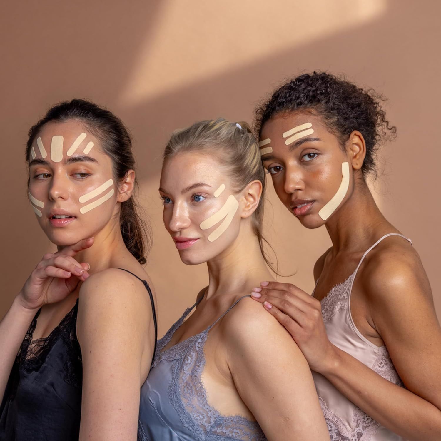Drie vrouwen met Kinesio Tape op het gezicht, verschillende huidtypen en haarkleuren.