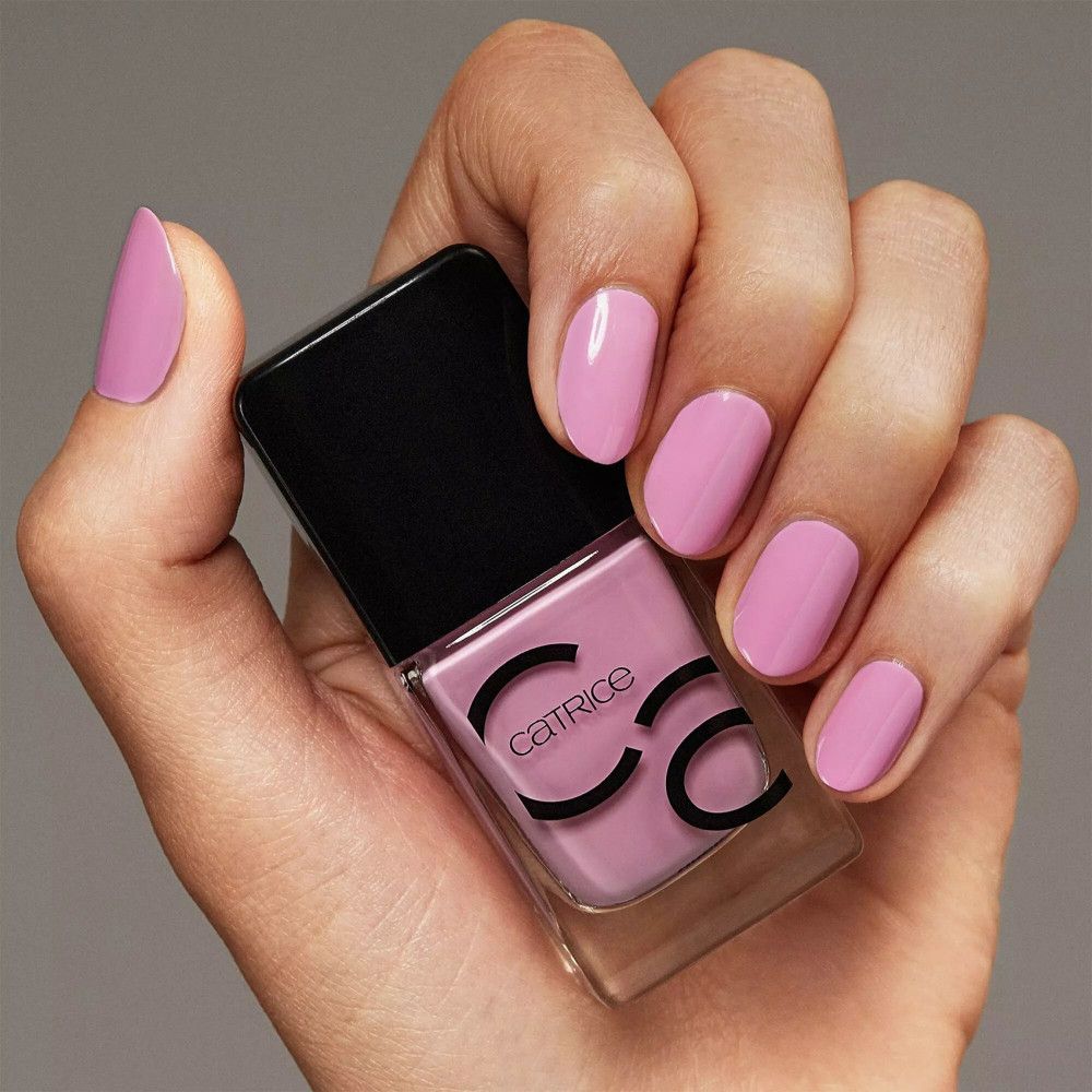 Main avec ongles vernis et flacon de vernis à ongles. Catrice est écrit sur le flacon.