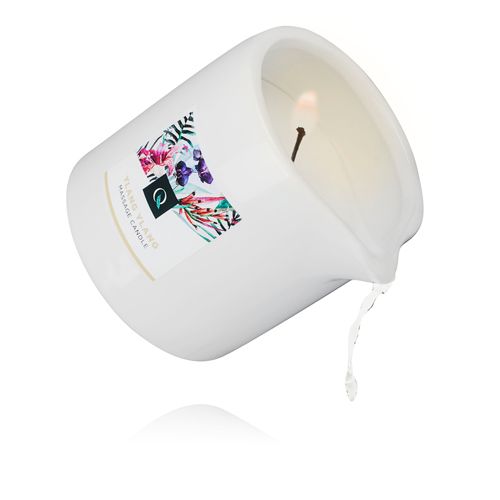 Witte massagekaars met schenktuit, schuin geplaatst. Etiket met bloemenpatroon en tekst: Ylang Ylang, Massage Candle.
