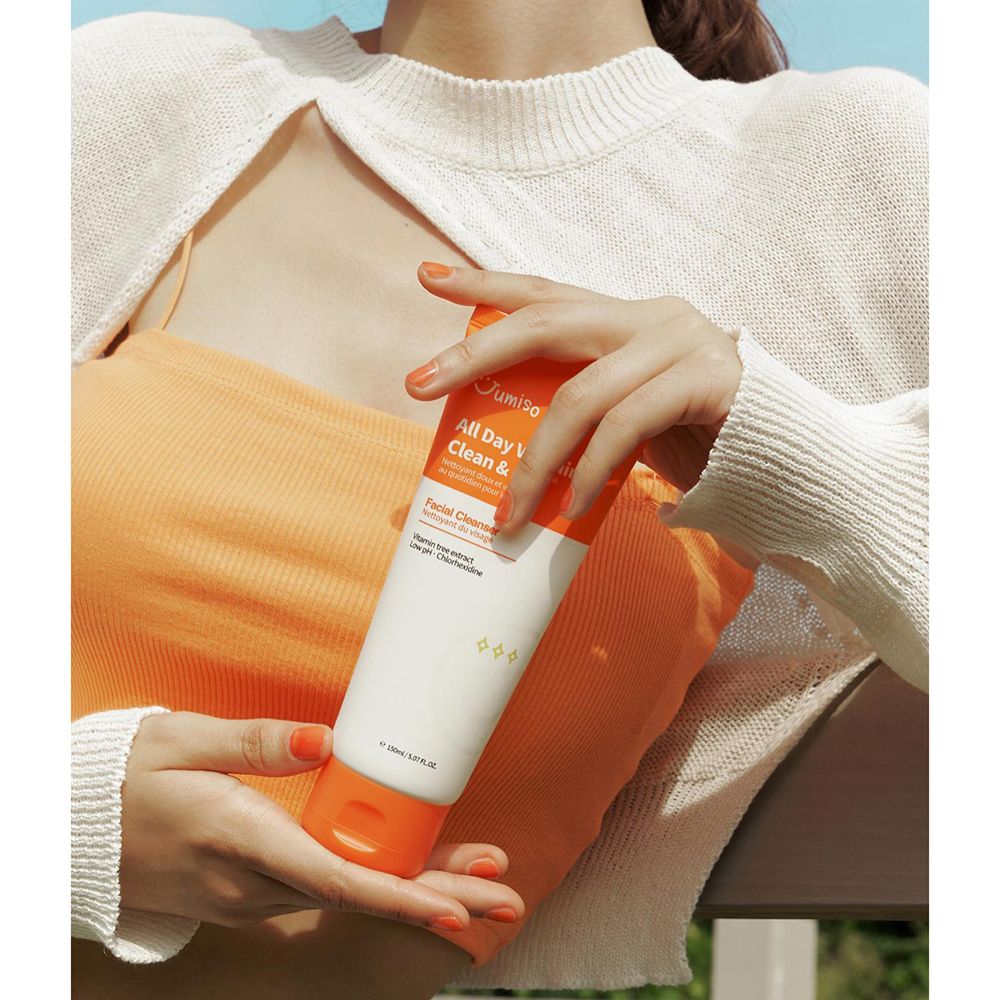 Persoon houdt een tube vast. Opschrift: All Day Vitamin Clean & Mild. Gezichtsreiniger.