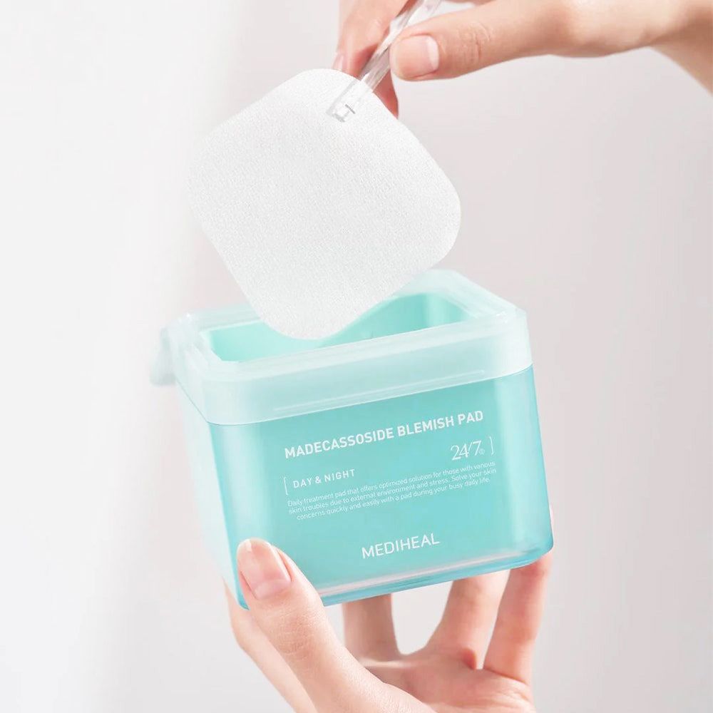 Mains tenant une boîte et un tampon. Boîte avec texte "MADECCASSOSIDE BLEMISH PAD". Marque: MEDIHEAL.