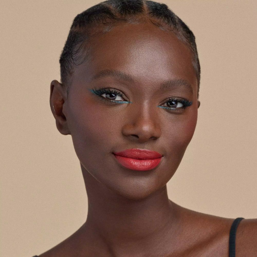 Portrait d'une femme avec du rouge à lèvres rouge. Elle a la peau foncée et porte de l'eye-liner.