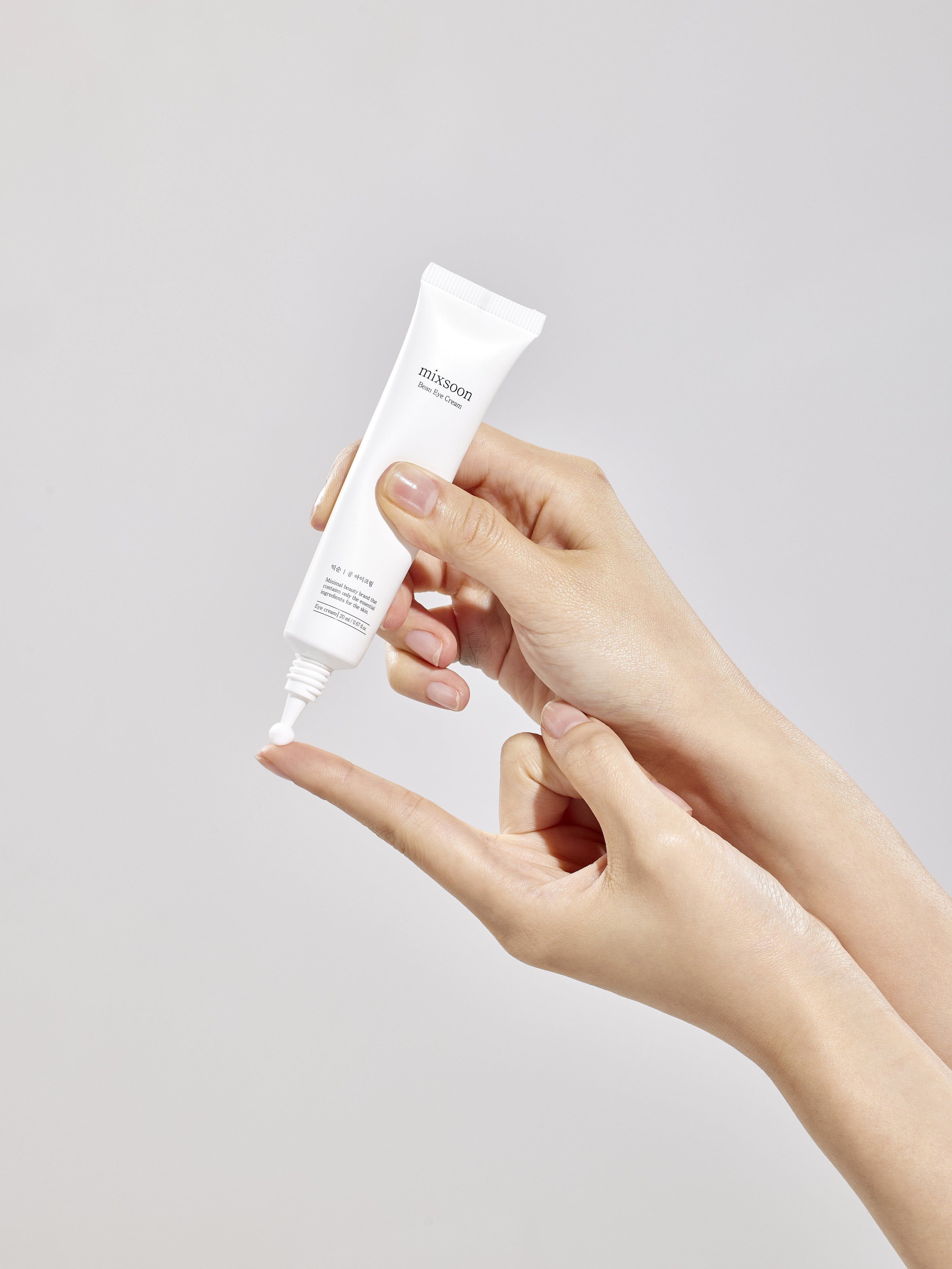 Main appliquant la crème pour les yeux Mixsoon sur un doigt.