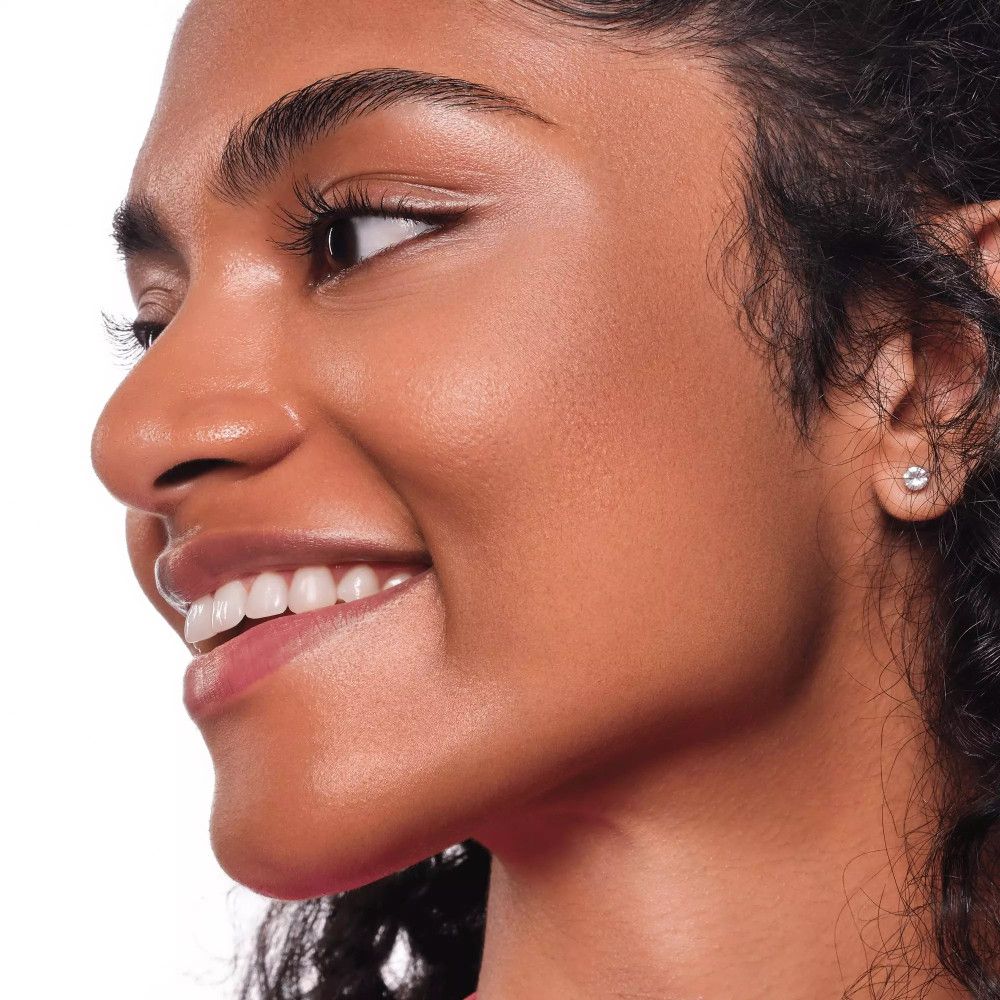 Gros plan d'un visage avec une peau bronzée. La personne sourit.