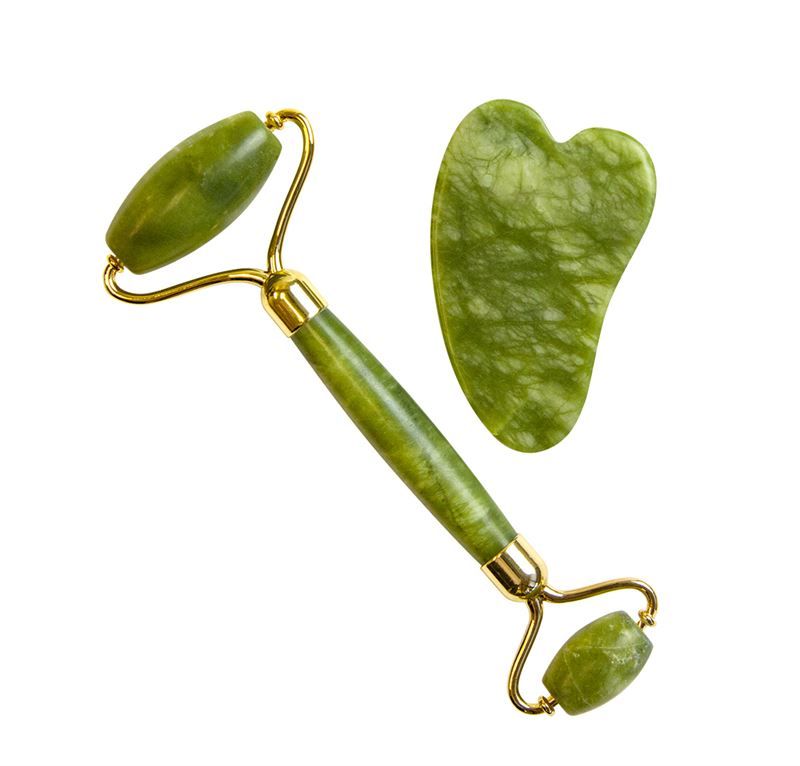 Rouleau de jade vert et pierre Guasha avec des accents dorés sur fond blanc.
