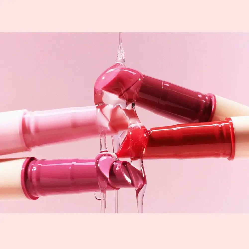 Verschillende lipgloss-stiften bedekt met een transparante vloeistof. Verschillende kleuren.