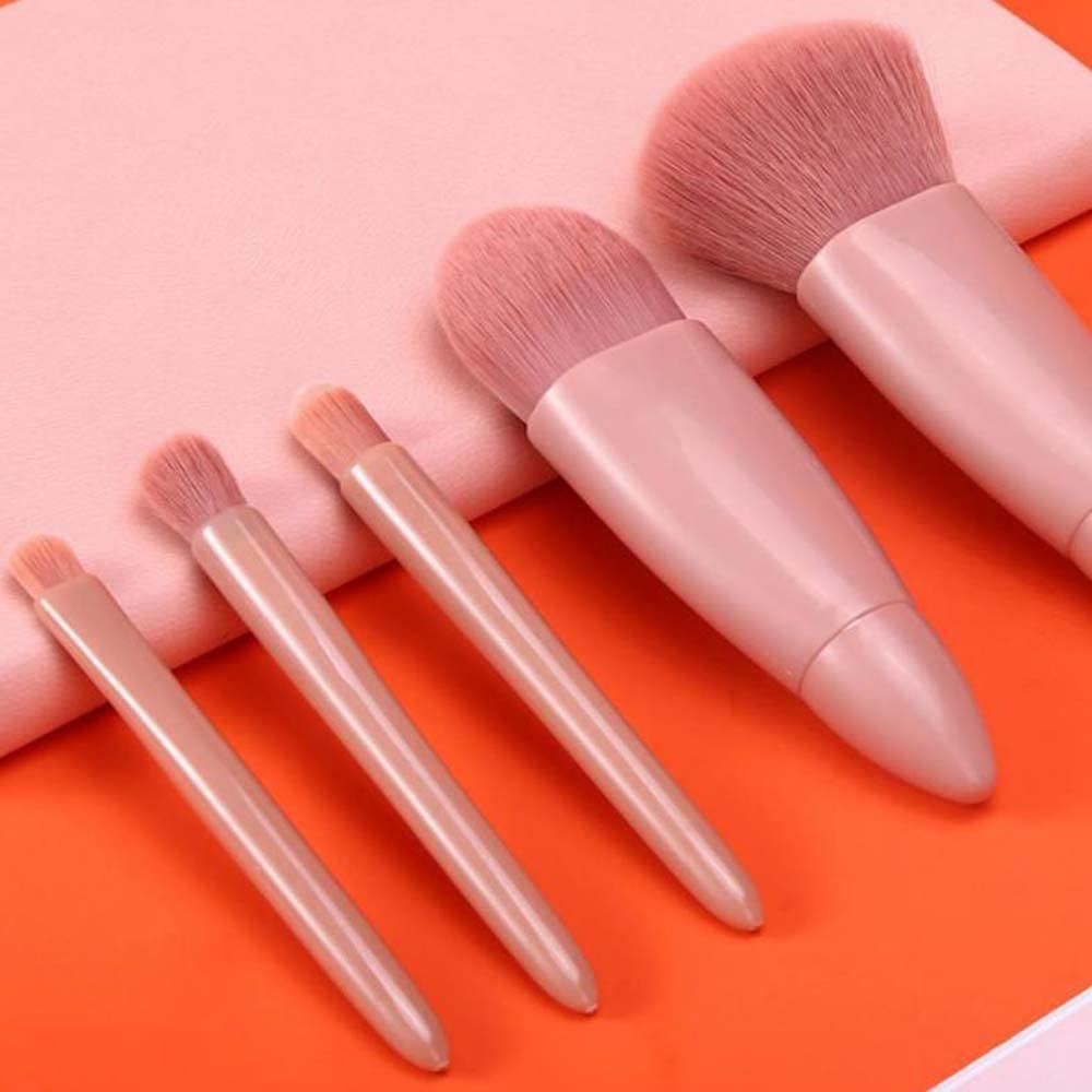 Cinq pinceaux de maquillage roses de différentes tailles et poils.