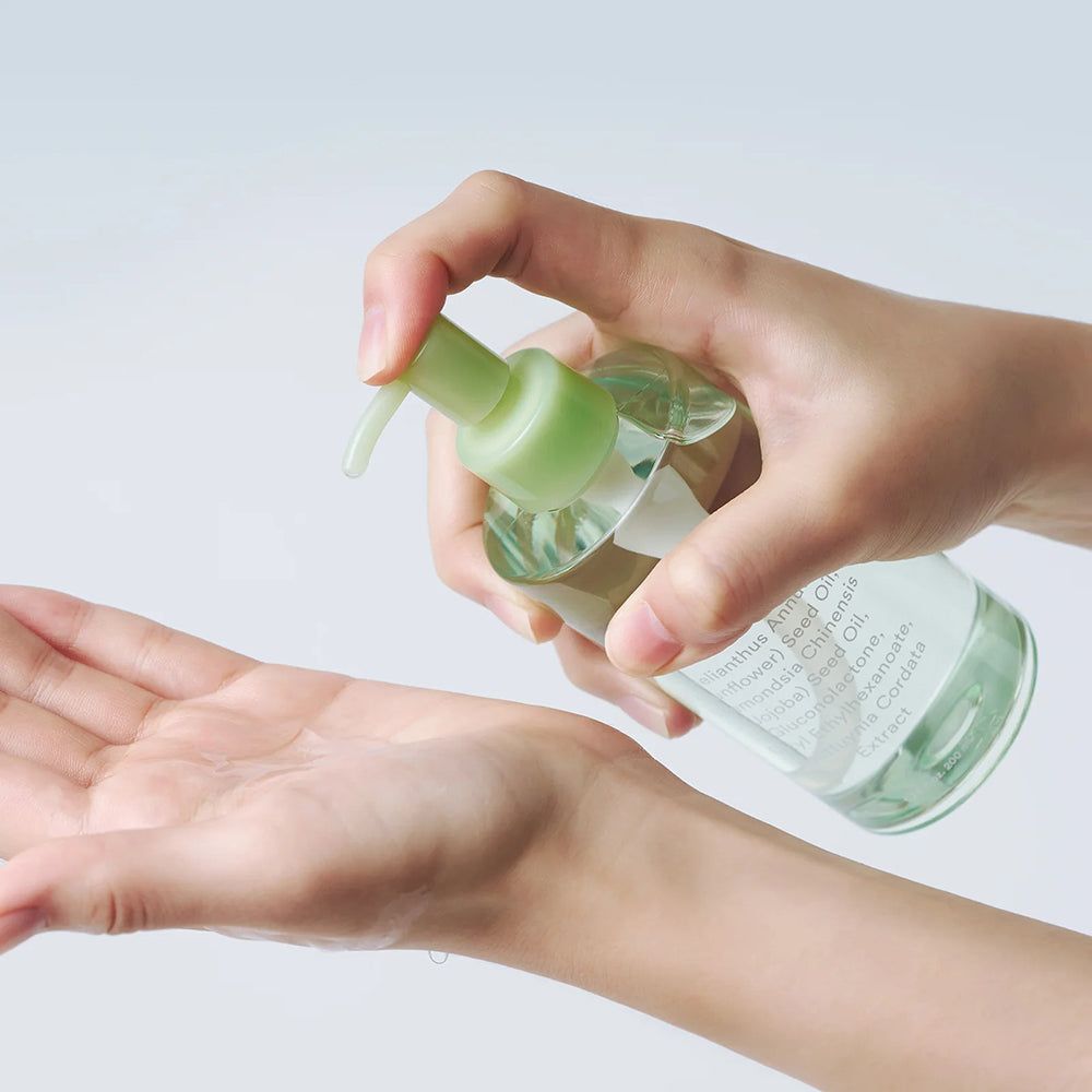 Hand die pompdispenser indrukt om heldere olie in de andere handpalm te doen.