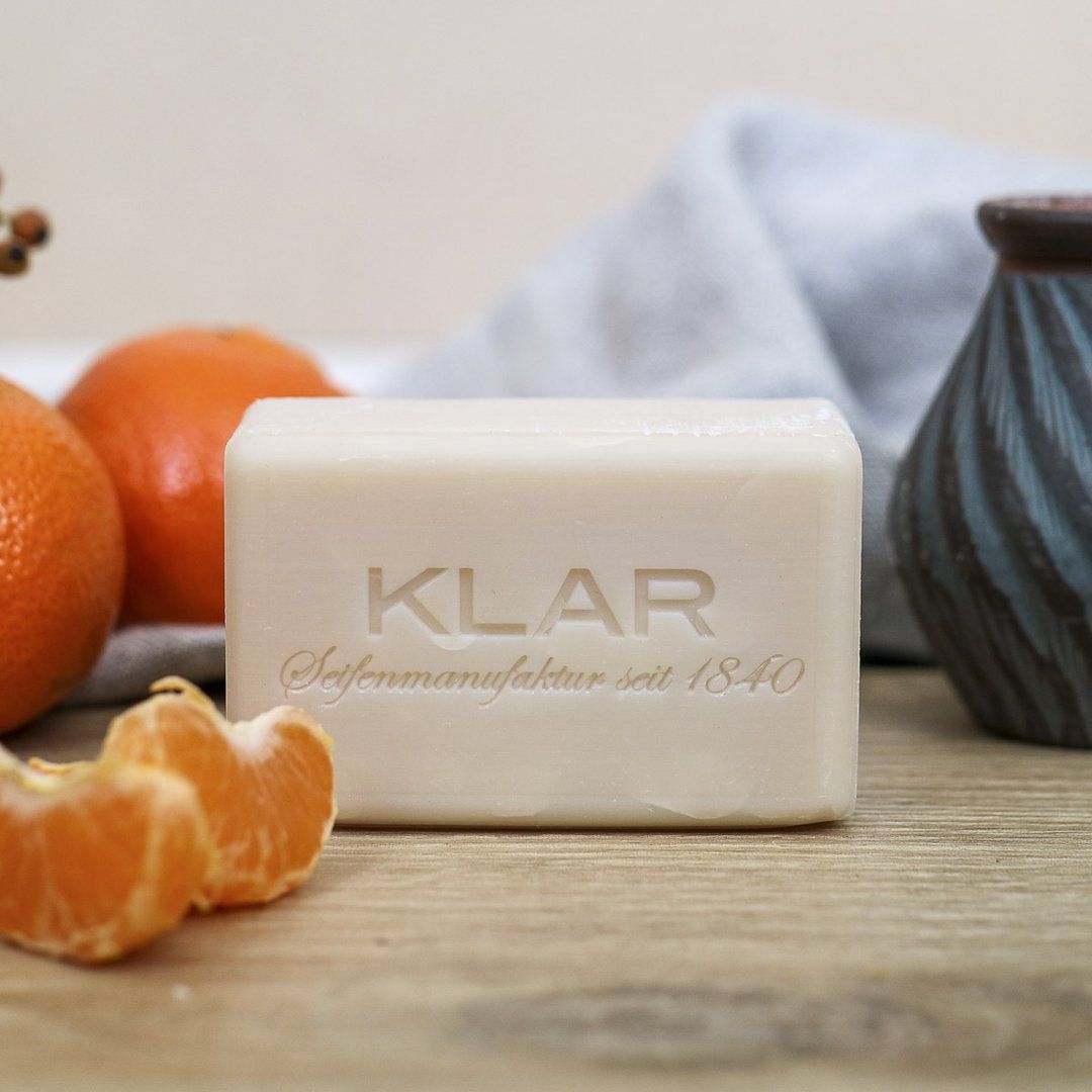 Shampooing solide avec logo Klar et inscription. À côté de mandarines et décorations.