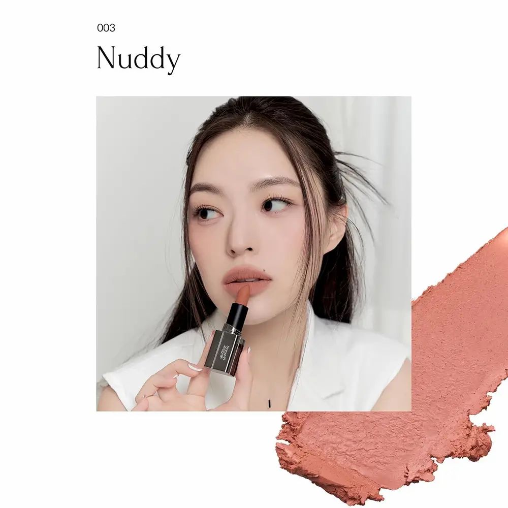 Vrouw houdt lipstick vast. Lipstick in Nuddy kleur. Opschrift: MUZIGAE MANSION. Daarnaast een veeg van de kleur. Tekst: 003 Nuddy.