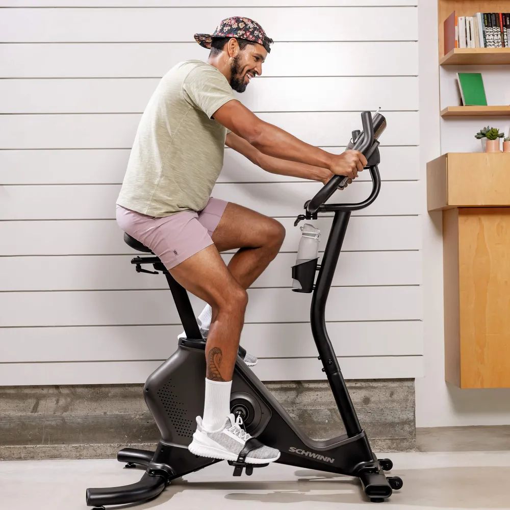Homme faisant de l'exercice sur un vélo d'appartement. Schwinn Fitness 590U. Bouteille d'eau.