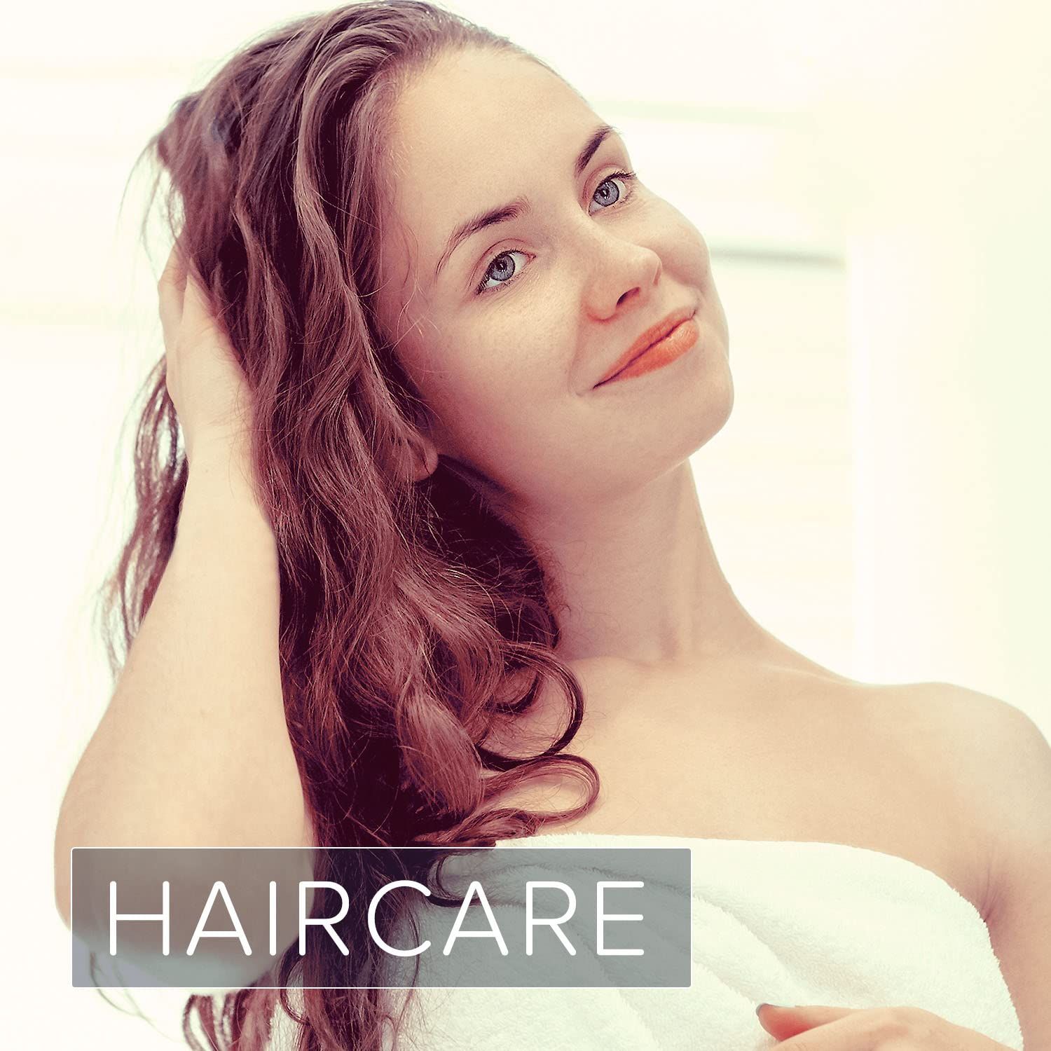 Femme touchant ses longs cheveux bruns. Texte "HAIRCARE" en bas. Lumière de fond claire.