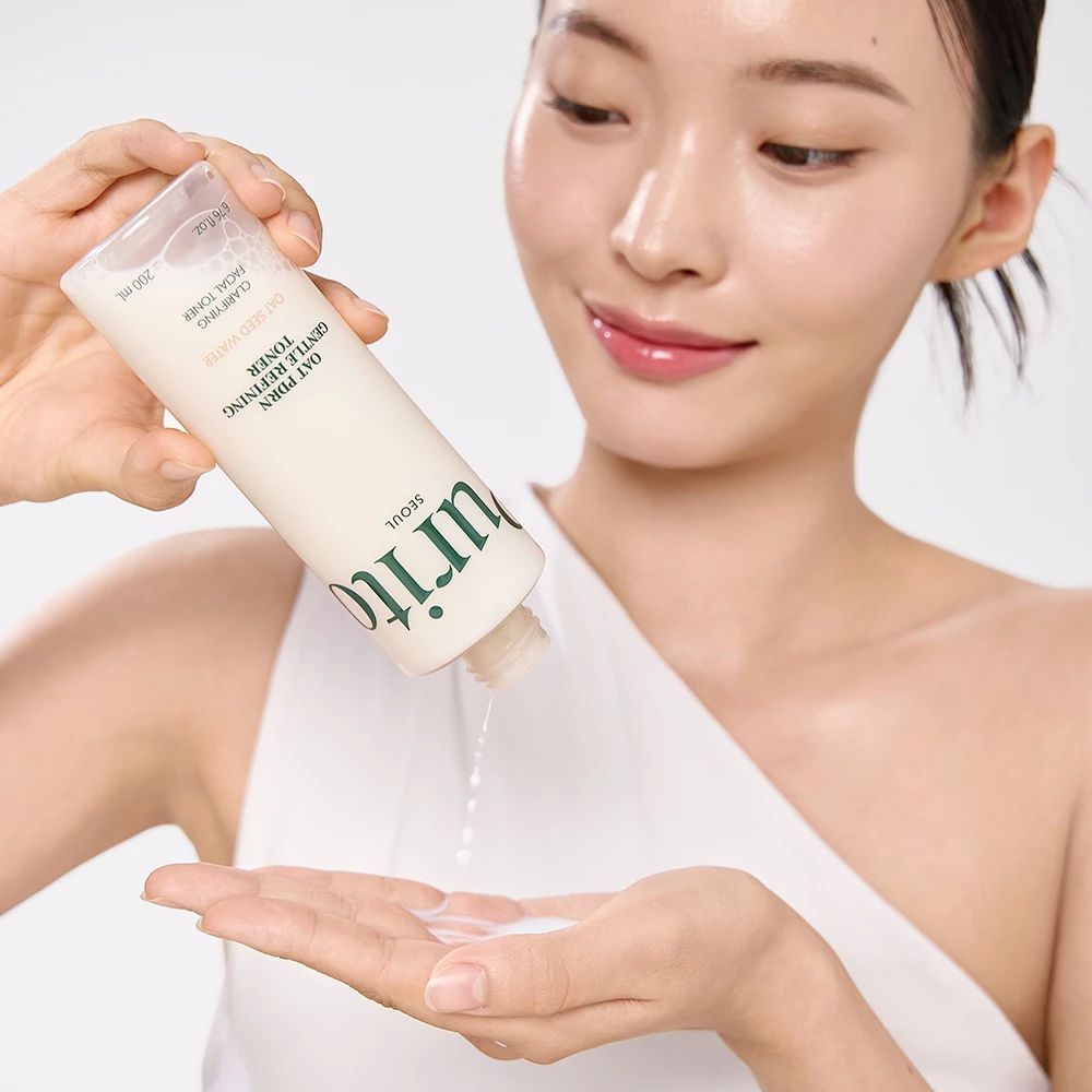 Vrouw giet toner uit een fles in haar hand. Opschrift: Purito, Oat PDRN Gentle Refining Toner.