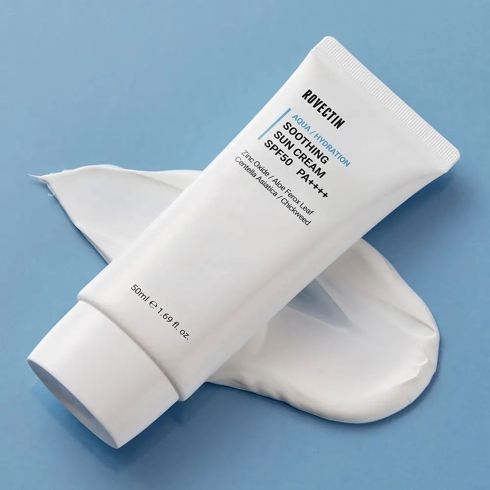 Witte tube ROVECTIN Aqua Soothing Sun Cream SPF50+ PA++++ op blauwe achtergrond. Crème ernaast. Tekst: Aqua/Hydration, 50ml e 1.69 fl. oz.