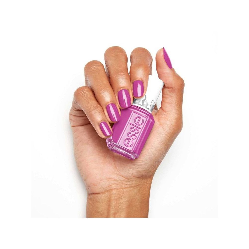 Hand houdt een flesje Essie nagellak vast. Nagels gelakt. Flesje met witte dop.