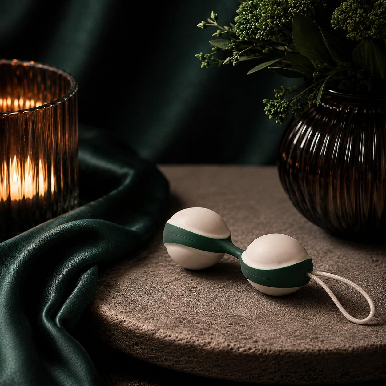 Balle duo pour le plancher pelvien avec cordon, blanc et vert, sur un socle.