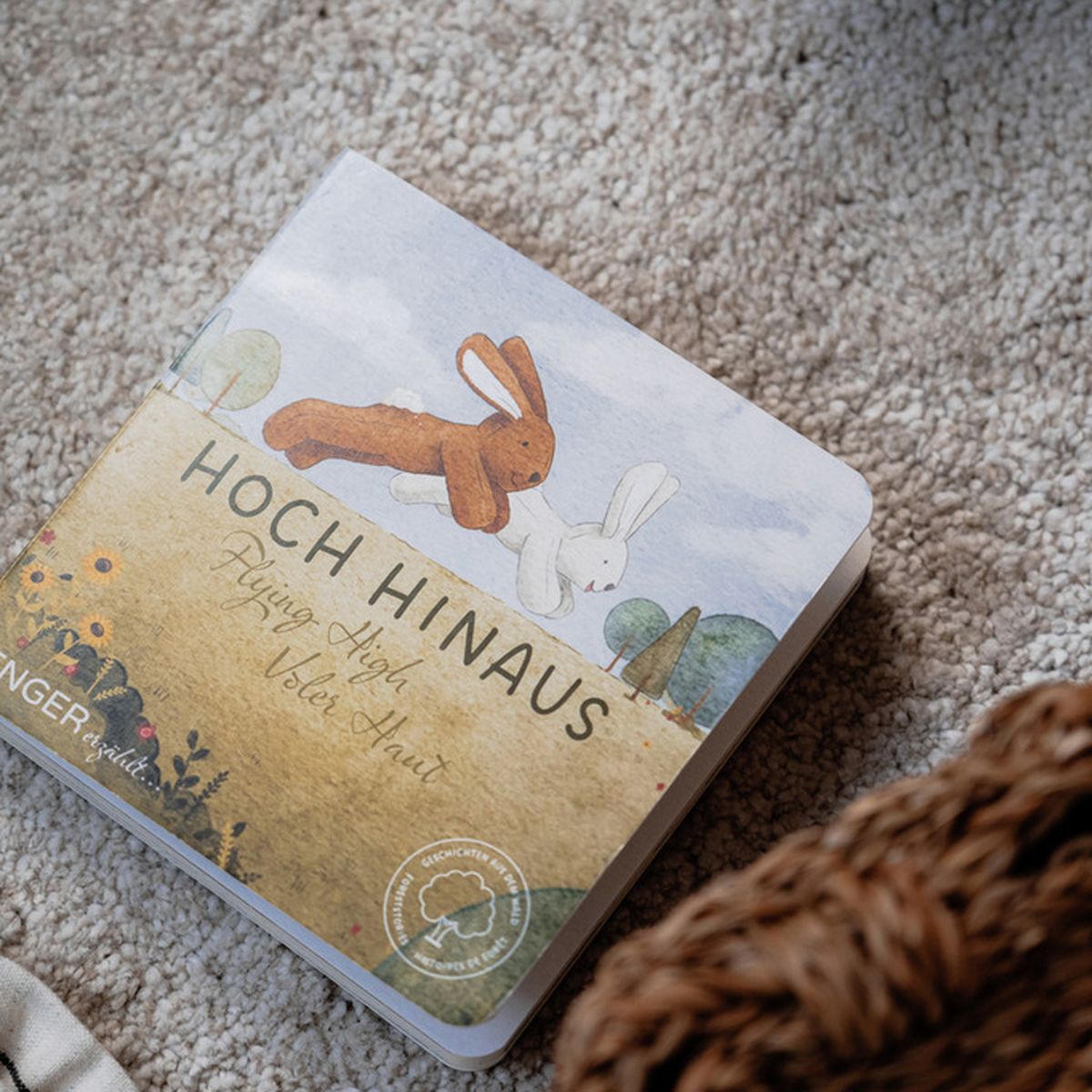 Livre avec illustrations de lapins. Titre : Hoch Hinaus. Marque : Senger. Sur un tapis.