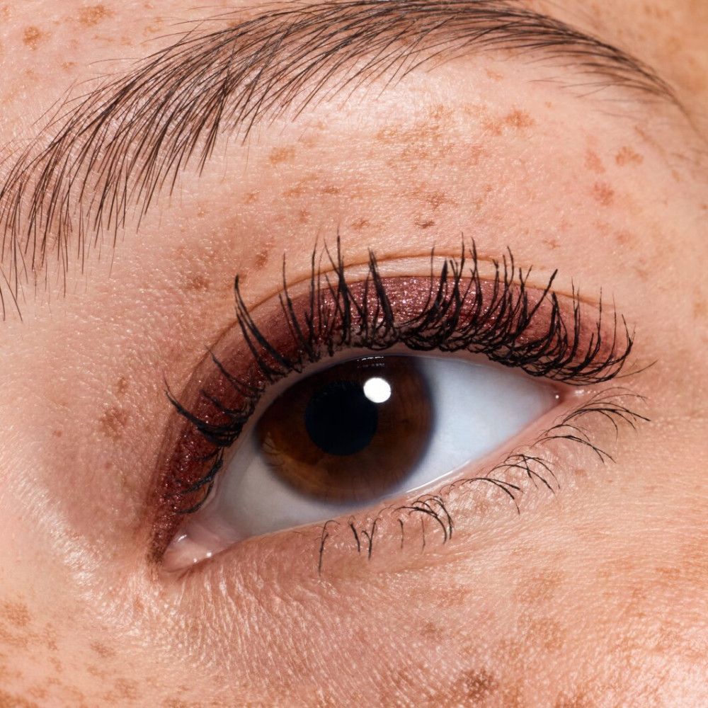 Gros plan sur un œil avec fard à paupières rouge et mascara. Iris marron.