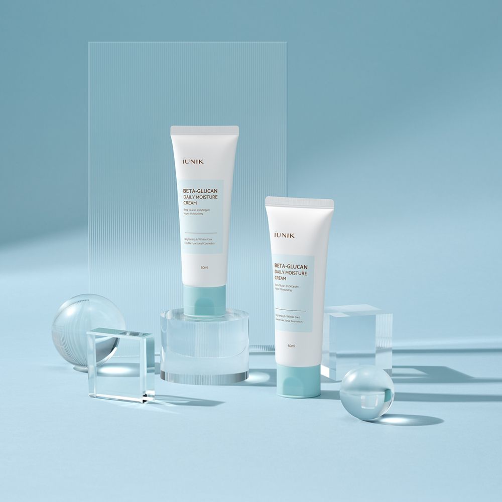 Deux tubes blancs avec bouchon bleu sur socle. Inscription: iUNIK, Beta-Glucan Daily Moisture Cream.