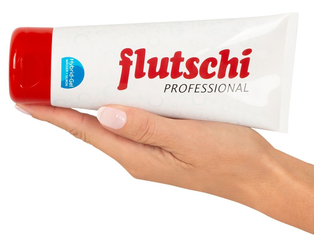 Tube tenu dans la main. Blanc avec bouchon rouge. Inscription : flutschi PROFESSIONAL. Hybrid-Gel.