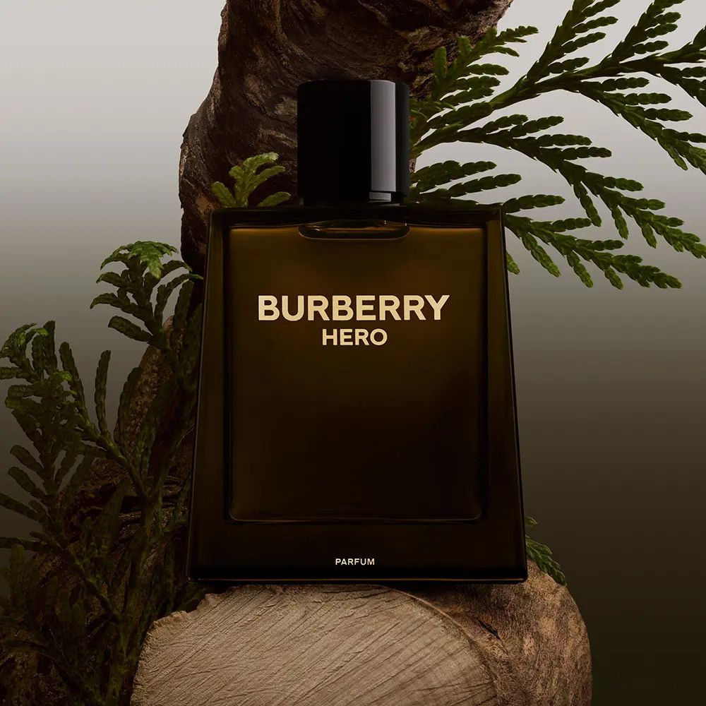 Flacon de parfum Burberry Hero. Bouteille marron avec bouchon noir, texte doré. Placé sur du bois et des branches.