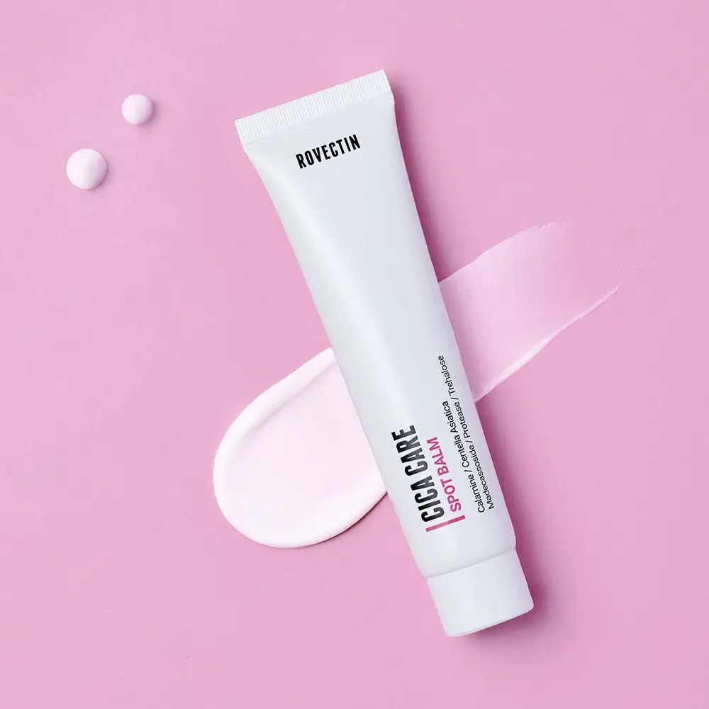 Witte tube op roze achtergrond. Productnaam Cica Care Spot Balm. Productmonster en druppels ernaast.