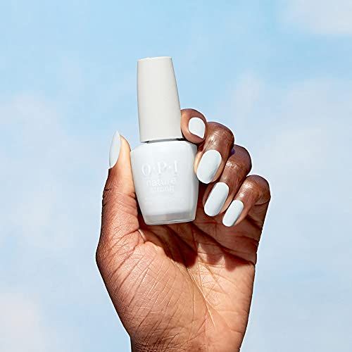 Main tenant un flacon de vernis à ongles bleu clair. OPI Nature Strong. Ciel bleu en arrière-plan.