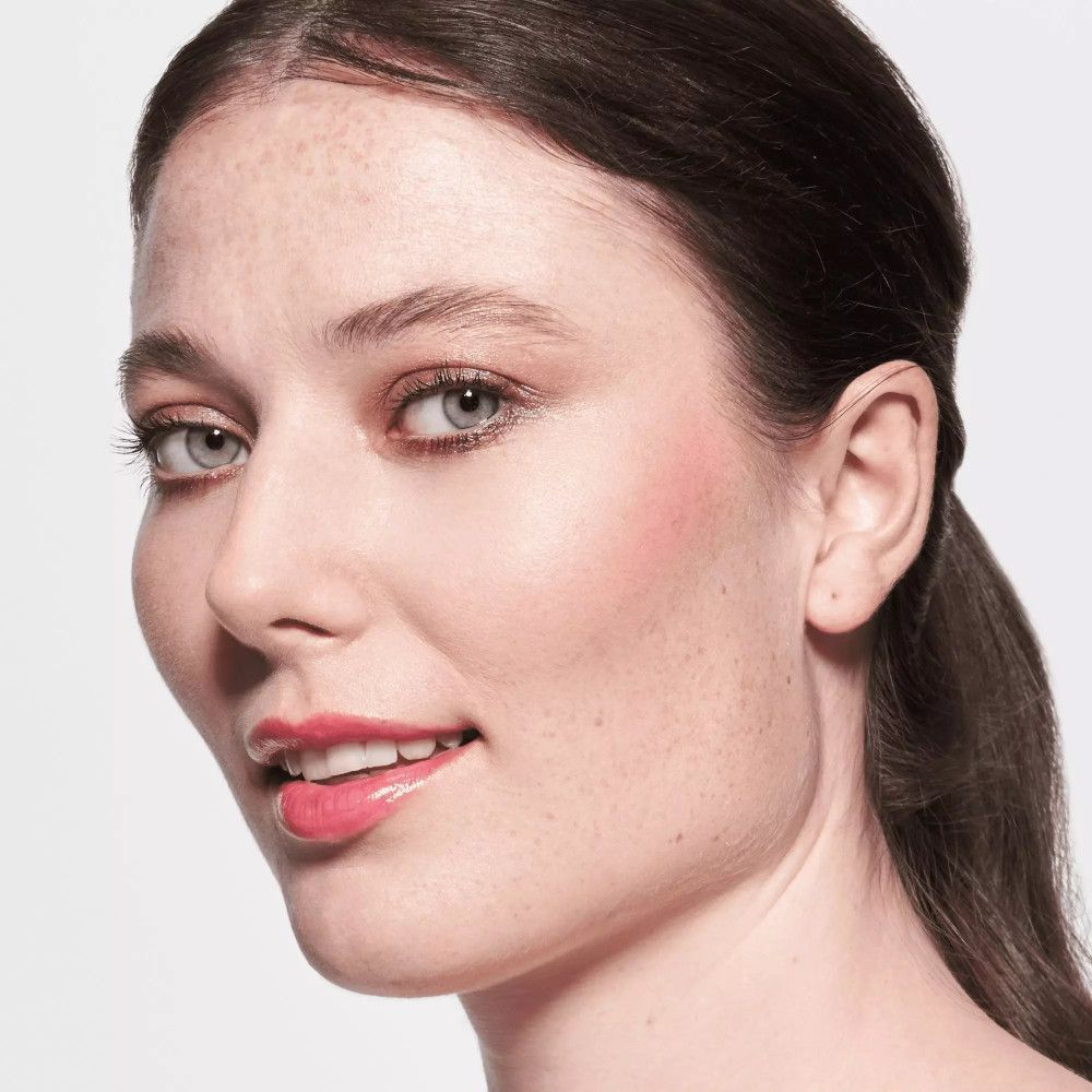 Portrait d'une femme portant du baume à lèvres. Lèvres roses, peau bronzée, taches de rousseur.